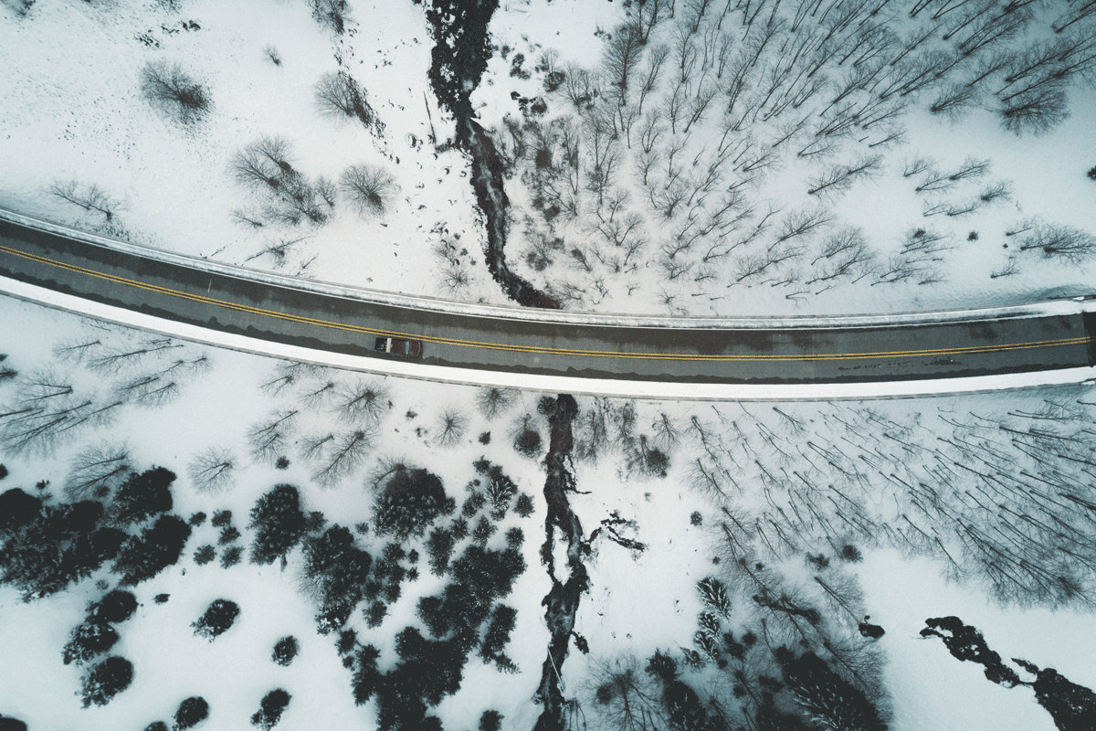 A remote road in snowy conditions with a car