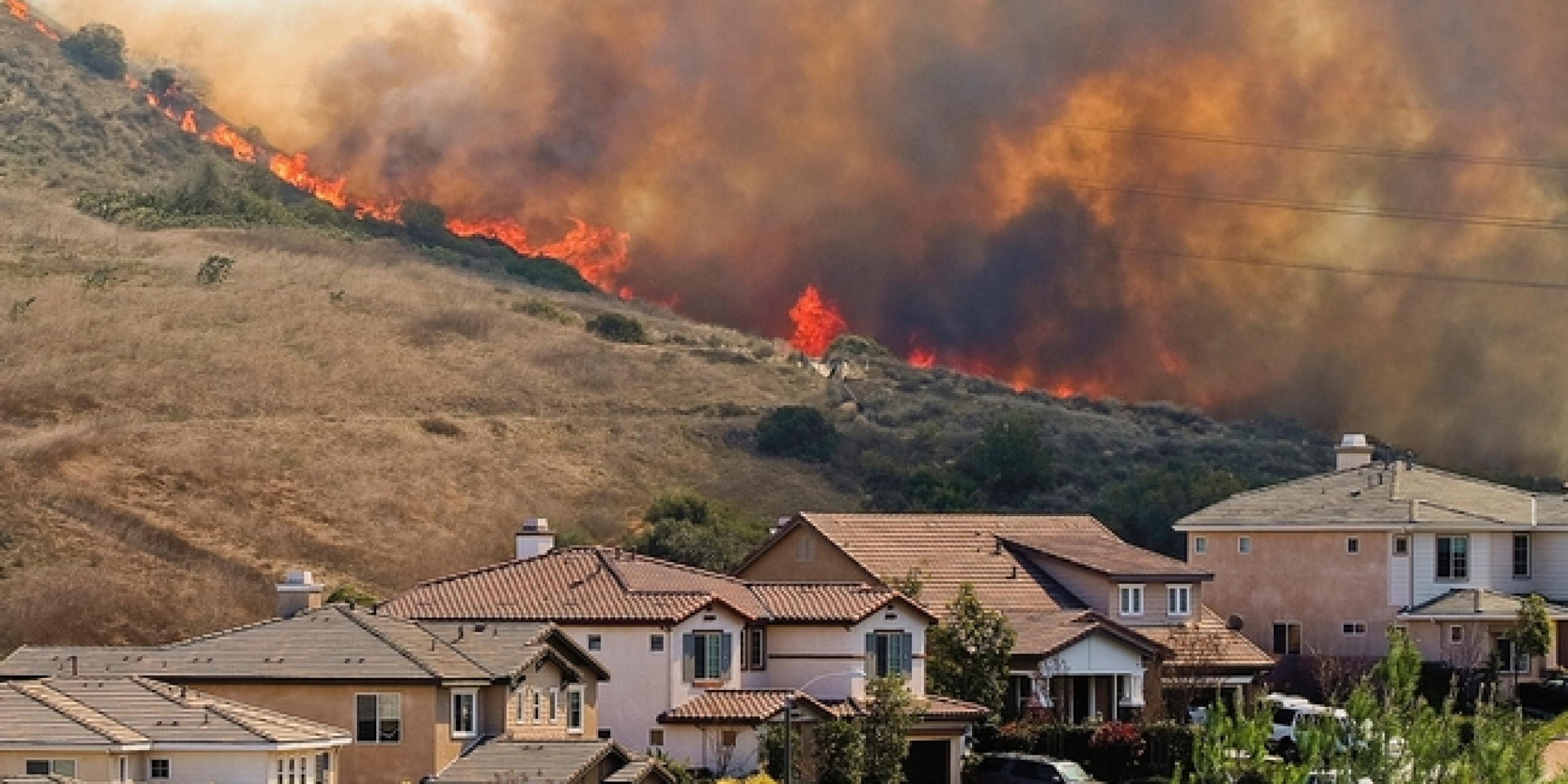 Wildfire burns on the ridge above a neighborhood. 