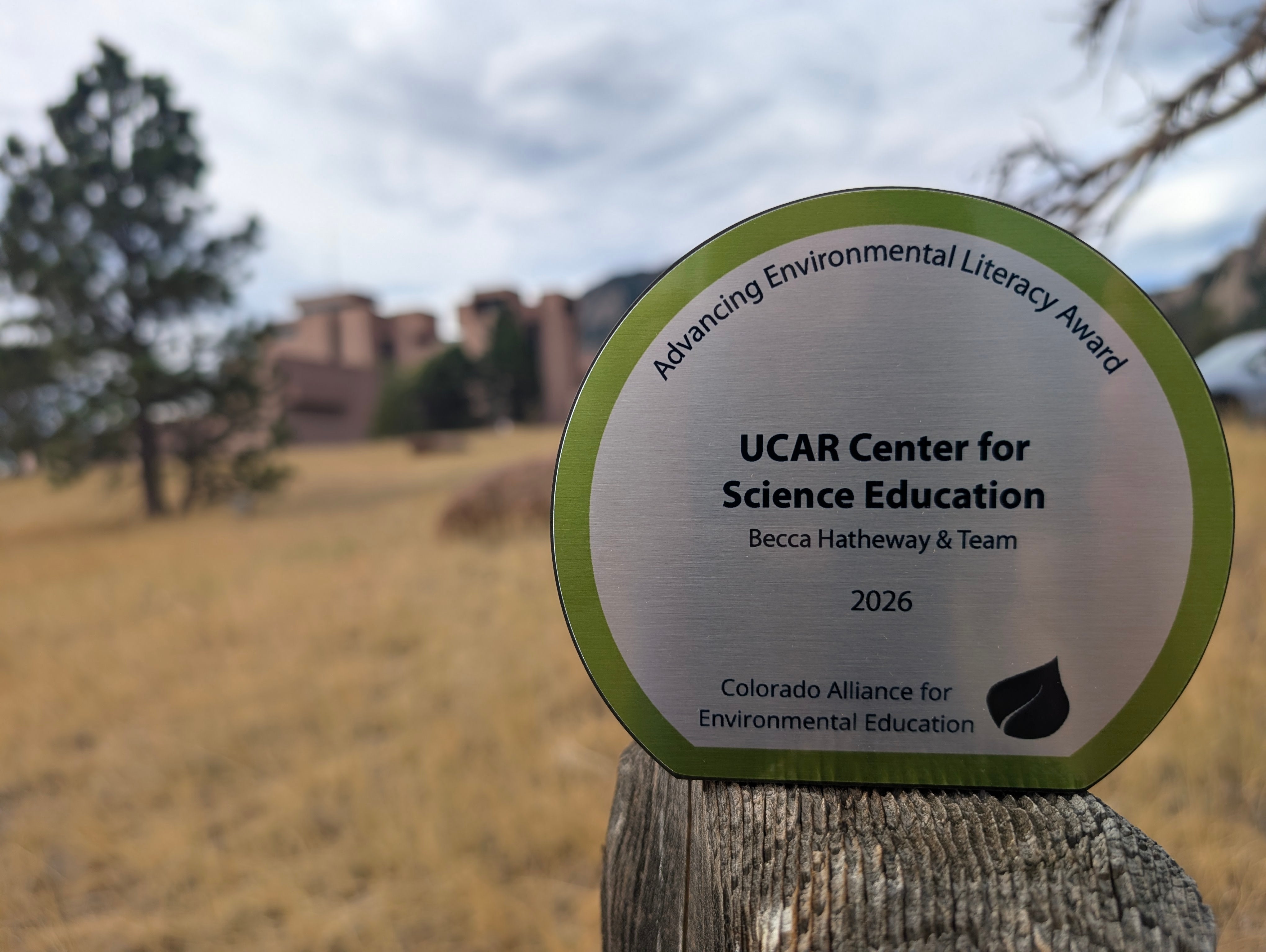 Award sits on a small ledge with a landscape of trees and building blurred in the background. 