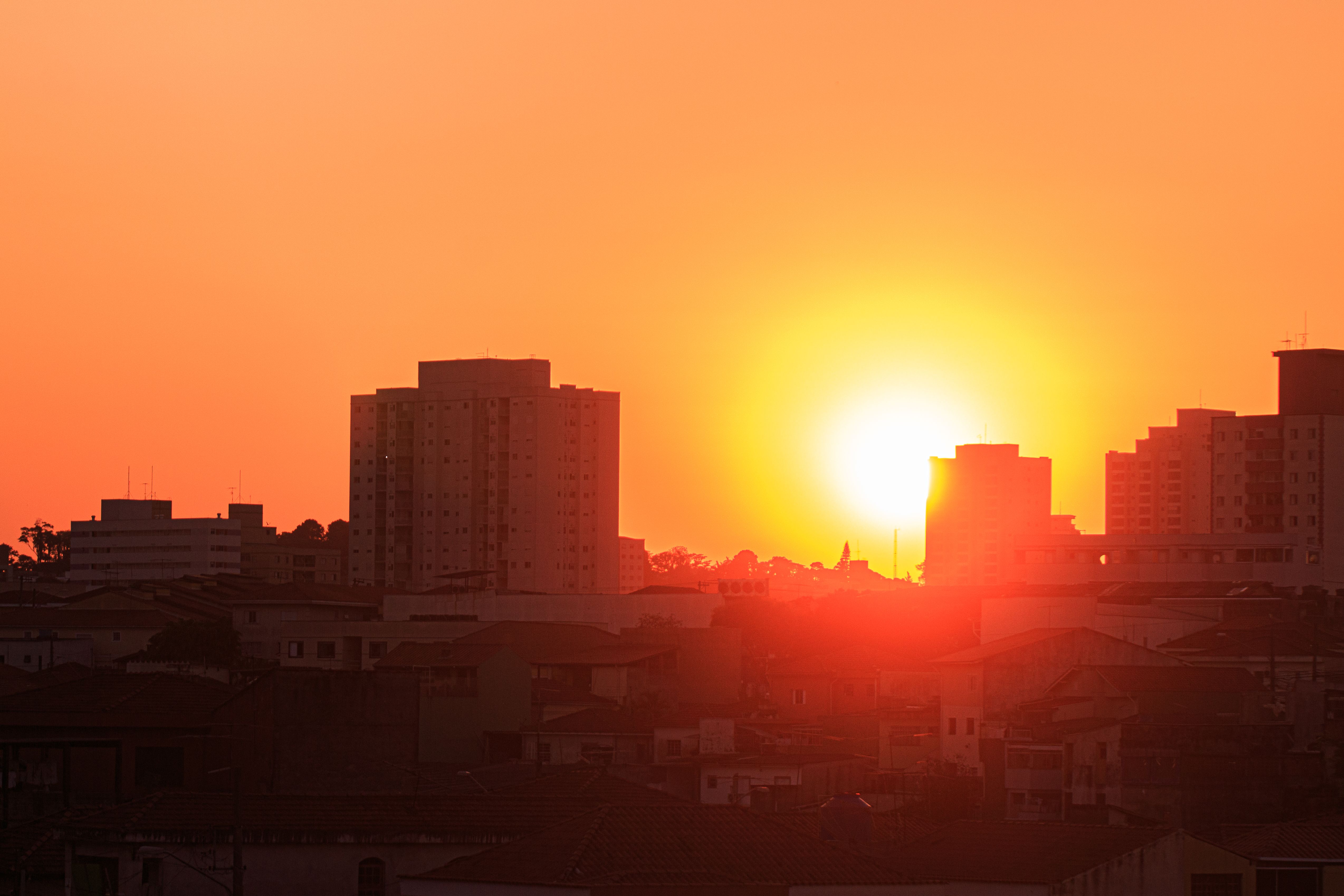 The Sun creates an orange background against an urban skyline. 