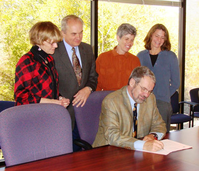 Photograph of Richard Anthes, signing a document and four other people
