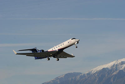 Photograph of a plane taking off, snow covered mountains in background