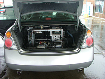Photograph of an open car trunk showing scientific equipment inside