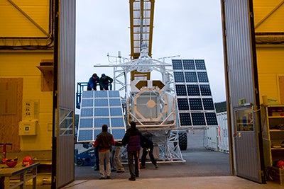Men loading scientific equipment, including solar panels, unto truck