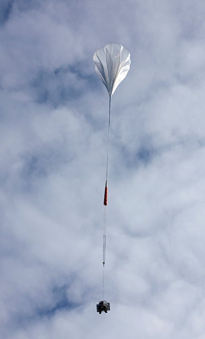 Large, white balloon, carrying equipment is launched