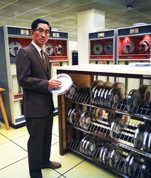 Photo of man standing next to computer magnetic tapes