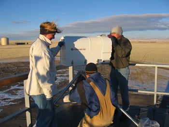 Three people working in a field on scietific equipment