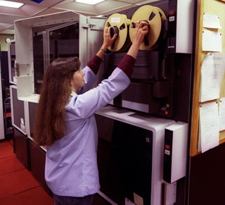Photo of a woman working with magnetic tapes for a computer
