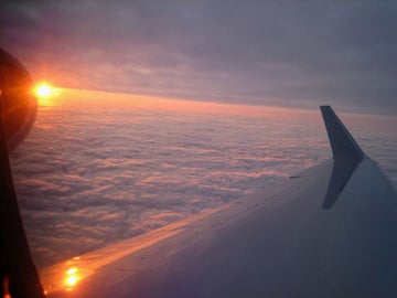 Photo from an airplane window of clouds and sun at sunset