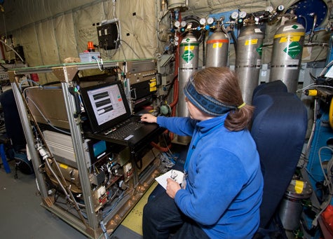 Photo of a woman sitting and working at scientific equipment