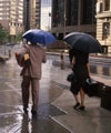 Photo of people with umbrellas, walking on city street in rain