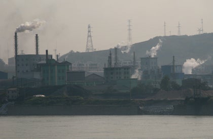 Photo of an urban landscape with visible pollution, river in foreground