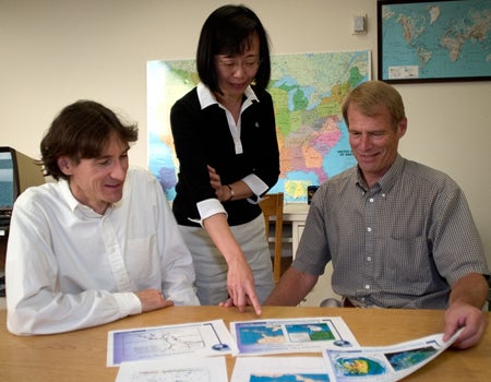 Photo of three people looking at maps