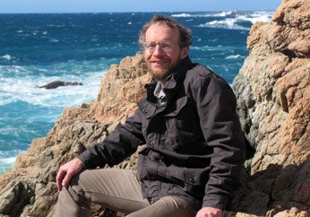 Richard Alley sitting on rocks by the sea