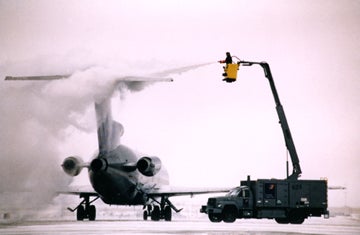 Worker hoses commercial jet with deicing fluid from "cherry picker"