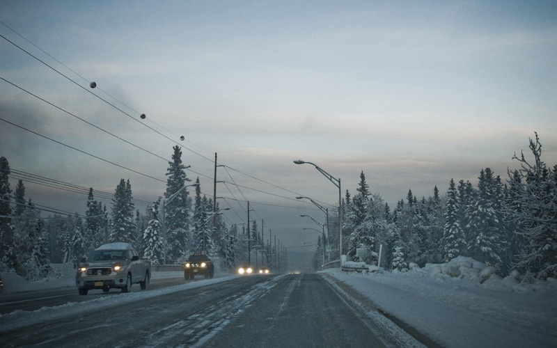 Cars with headlights on a highway near Fairbanks, AK, during midwinter