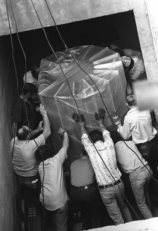Group of men lowering the computer into the Mesa Lab with ropes.