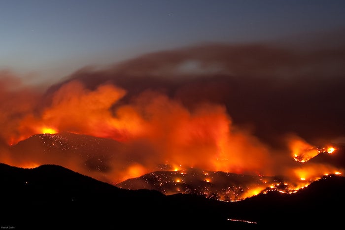 Orange flames and smoke covering the foothills at night.