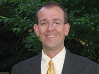Jim Hurrell in a suit with trees in the background.