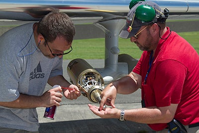 Two men working beneath aircraft wing.