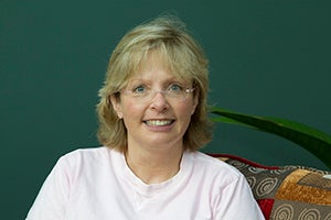 Reta against a green backdrop with part of a plant showing.