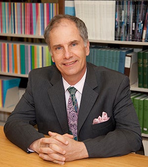Tom Bogdan in his office with books behind him.