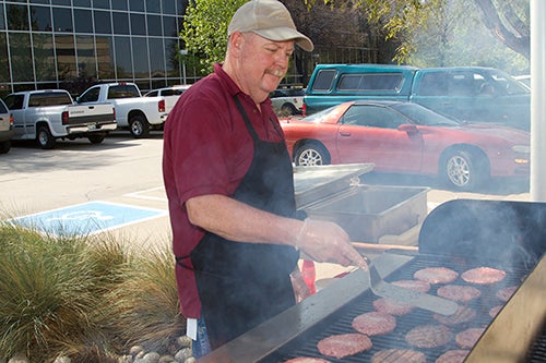 Hal Segal flipping burgers at grill.