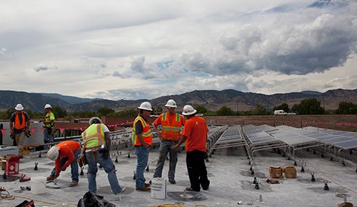 Construction workers on the roof installing solar panels.