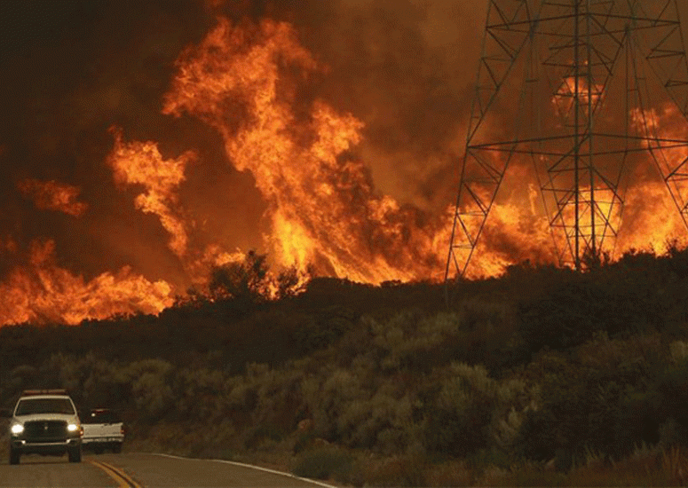 Emergency vehicles drive past California wildfire