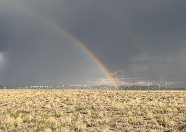 Two rainbows over a row of flux towers in a field. 