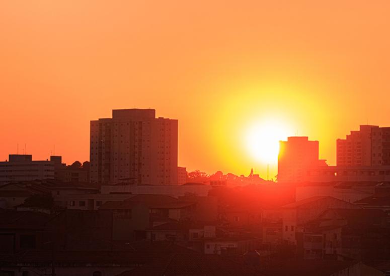 The Sun creates an orange background against an urban skyline. 