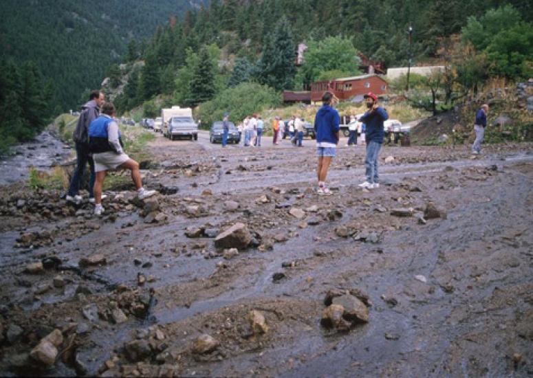 Photograph of people standing at washed-out road after flood
