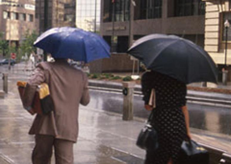 Photo of people walking in rain and holding umbrellas
