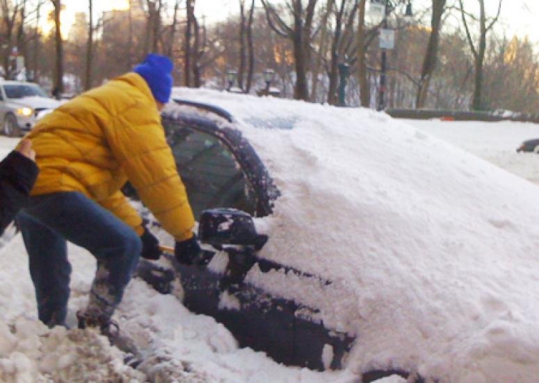 A motorist near Central Park tries to enter his snowbound vehicle