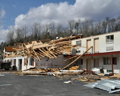 Motel damaged by tornado in Saylerville, KY, with bare trees in background