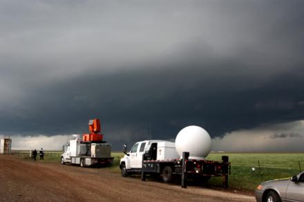 Mobile radar trucks with storm behind them
