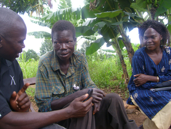Ugandan villagers discussing reporting plague cases via cell phone