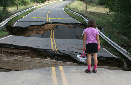 Constructing roads that take changing weather into account: girl looks at washed out road in Colorado